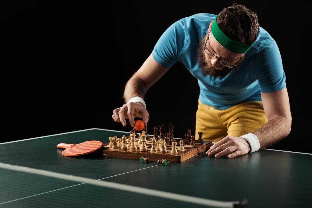 jogador de tênis colocando bola no tabuleiro de xadrez na mesa de tênis isolado em preto
 - Foto, Imagem