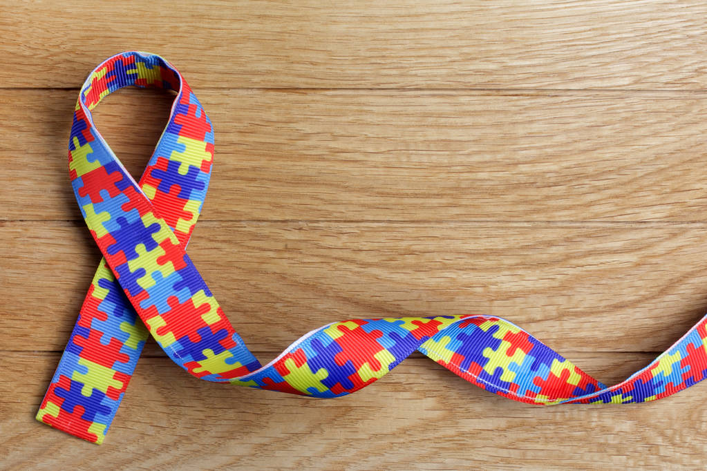 Wereld autisme bewustzijn en trots dag of maand met puzzel patroon lint op houten achtergrond. - Foto, afbeelding