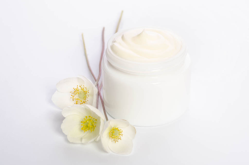Fleurs mignonnes et un pot de crème naturelle pour le corps isolé sur blanc
 - Photo, image