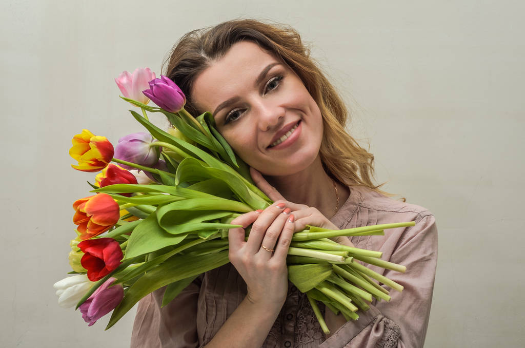 Jonge charmante meisje met een boeket bloemen - multi-gekleurde tulpen - Foto, afbeelding