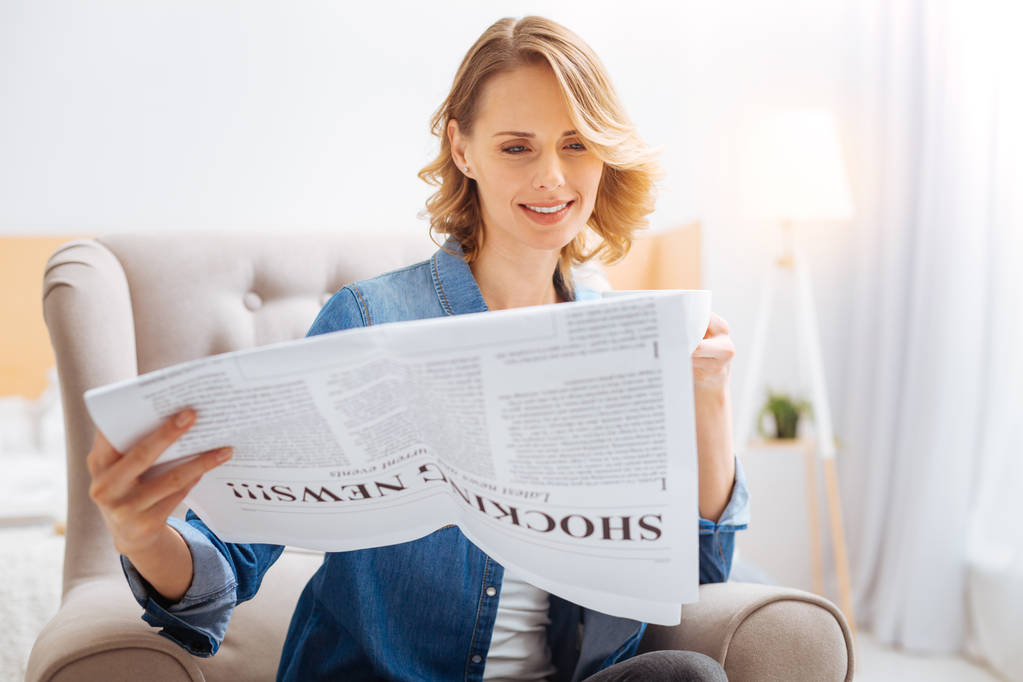Csendes vidám nő nézi az oldalon egy újságot, és mosolyogva - Fotó, kép