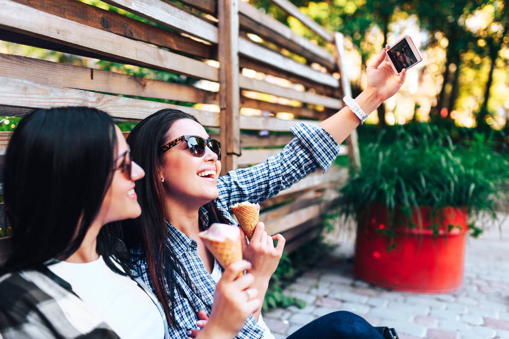zwei schöne Frauen essen Eis und machen Selfie - Foto, Bild