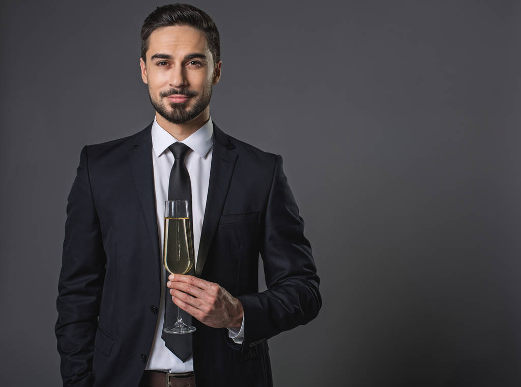 Asertivní atraktivní podnikatel drží sklenku šumivého vína - Fotografie, Obrázek
