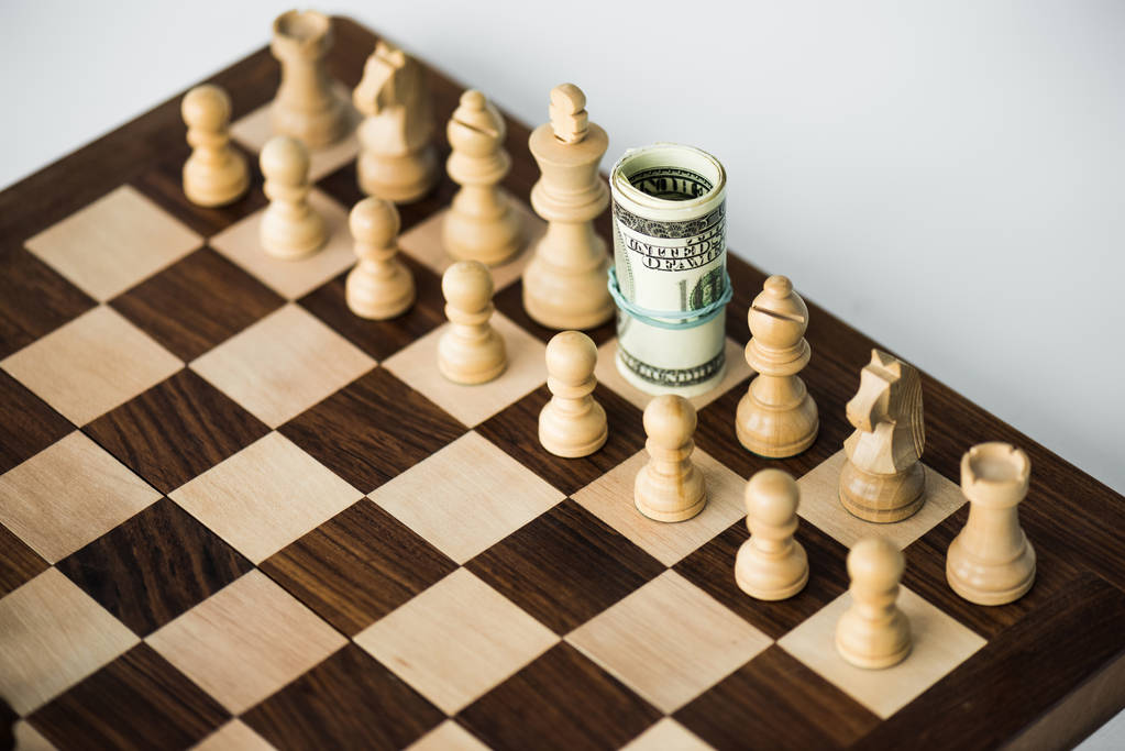 Schachbrett mit Bargeld und weißen Schachfiguren auf weißer Oberfläche - Foto, Bild