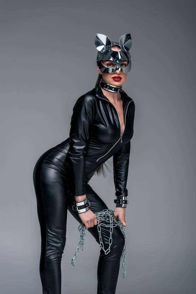 Jeune femme séduisante portant un costume de chat et un masque tenant la chaîne isolé sur gris
 - Photo, image