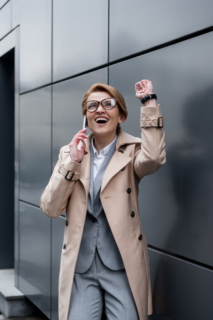 emocionado gesto de mujer de negocios hablando en el teléfono inteligente en la calle
 - Foto, imagen
