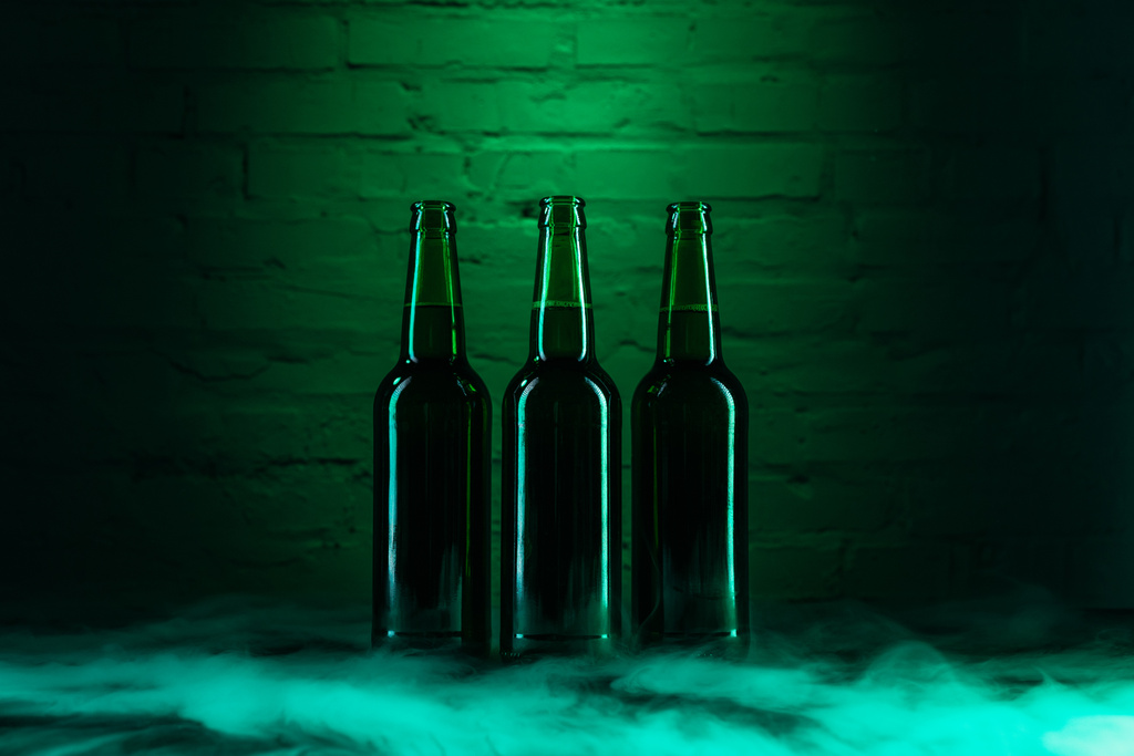 τρεις Ανοίξτε πράσινη beer φιάλες και να καπνίζουν σε πράσινο φως  - Φωτογραφία, εικόνα