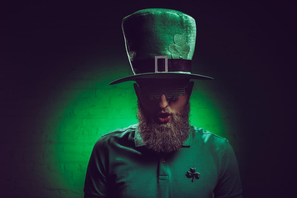 πορτρέτο γενειοφόρου νεαρού σε πράσινο ιρλανδικό καπέλο και αστεία γυαλιά - Φωτογραφία, εικόνα