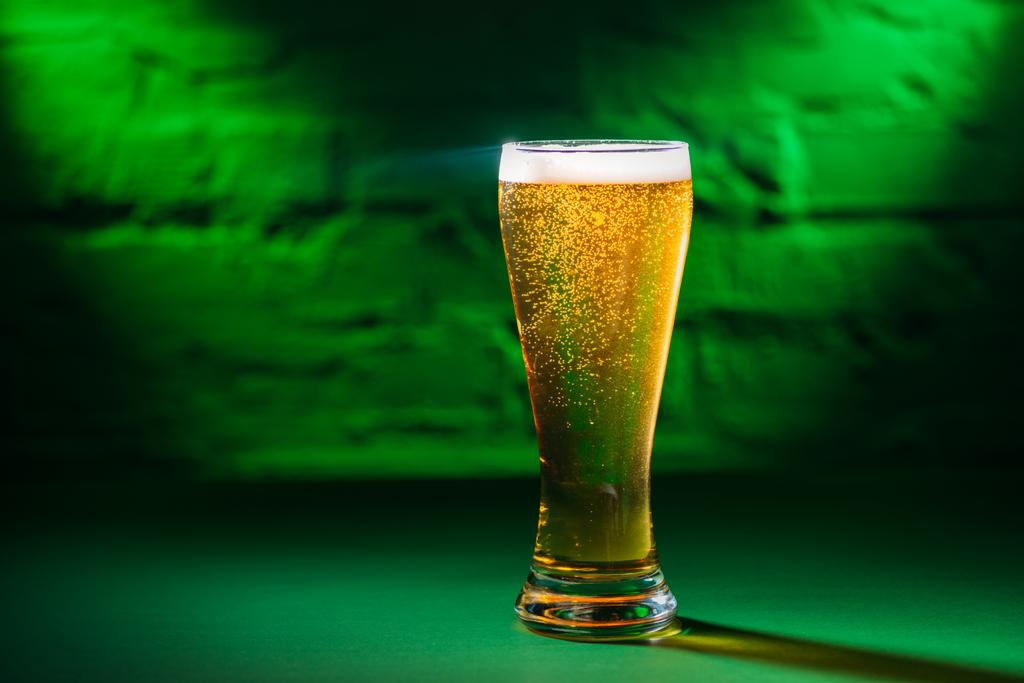 close-up view of glass with fresh cold beer in green light  - Photo, Image