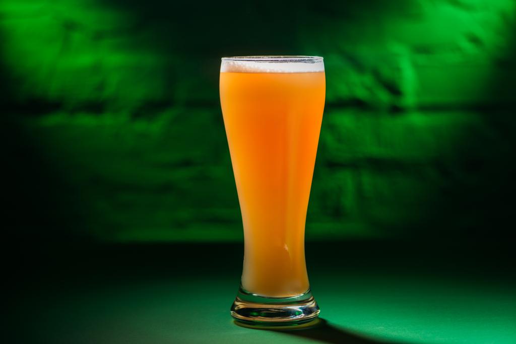 Nahaufnahme von Glas mit frischem, kaltem Bernstein-Bier in grünem Licht  - Foto, Bild