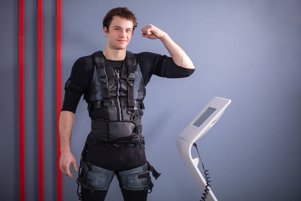 uomo vicino alla macchina EMS, stimolazione muscolare, mostrando bicipiti
 - Foto, immagini