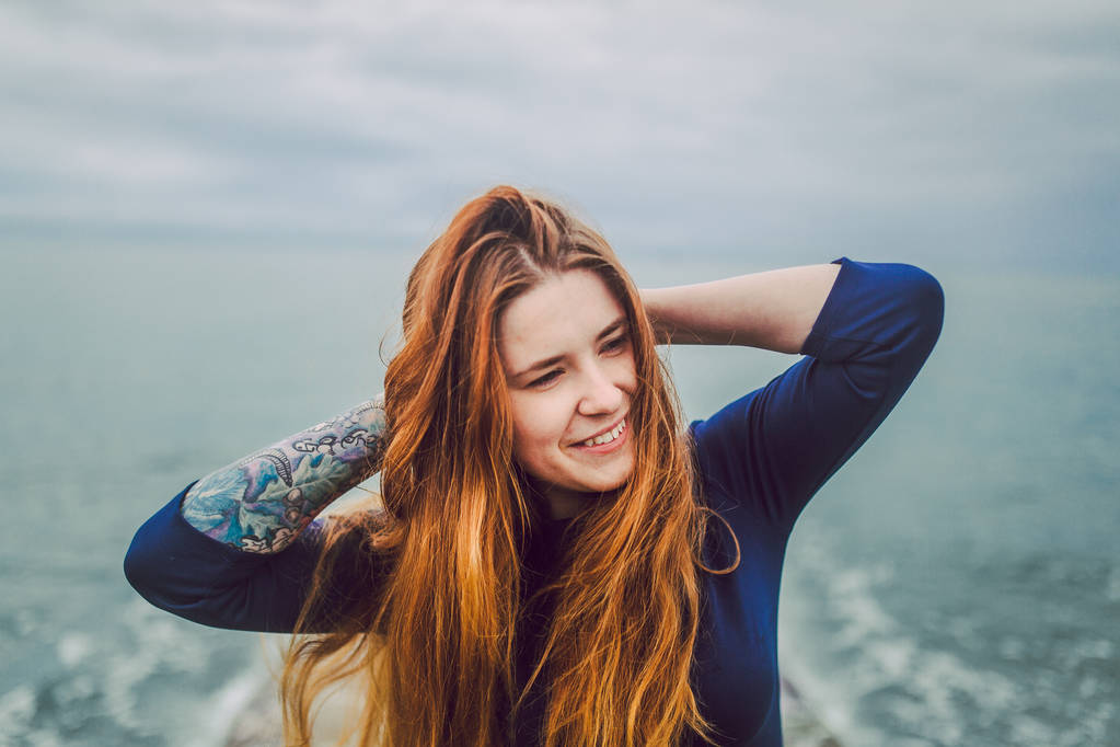 muotokuva onnellinen nainen pitkät punaiset hiukset sininen mekko meren rannalla pilvinen päivä
 - Valokuva, kuva