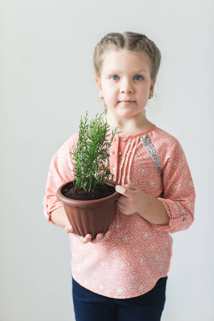 Aranyos gyermek gazdaság egy cserepes növény - Fotó, kép