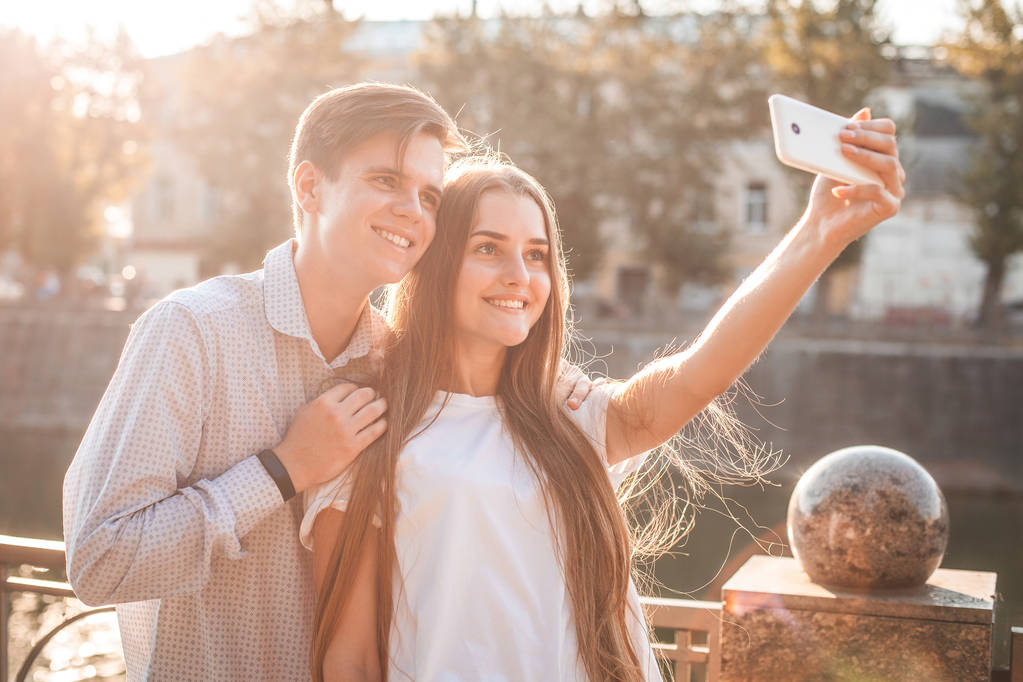 joven hombre y mujer tomando selfie en el teléfono inteligente en la calle
 - Foto, imagen