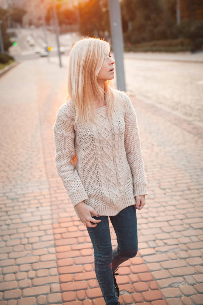 Молодая блондинка, идущая по городской улице на закате
 - Фото, изображение