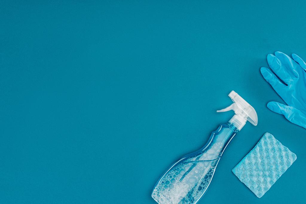 κάτοψη του σπρέι μπουκάλι και ελαστικό γάντι με πλύσιμο σφουγγαριών που απομονώνονται σε μπλε - Φωτογραφία, εικόνα
