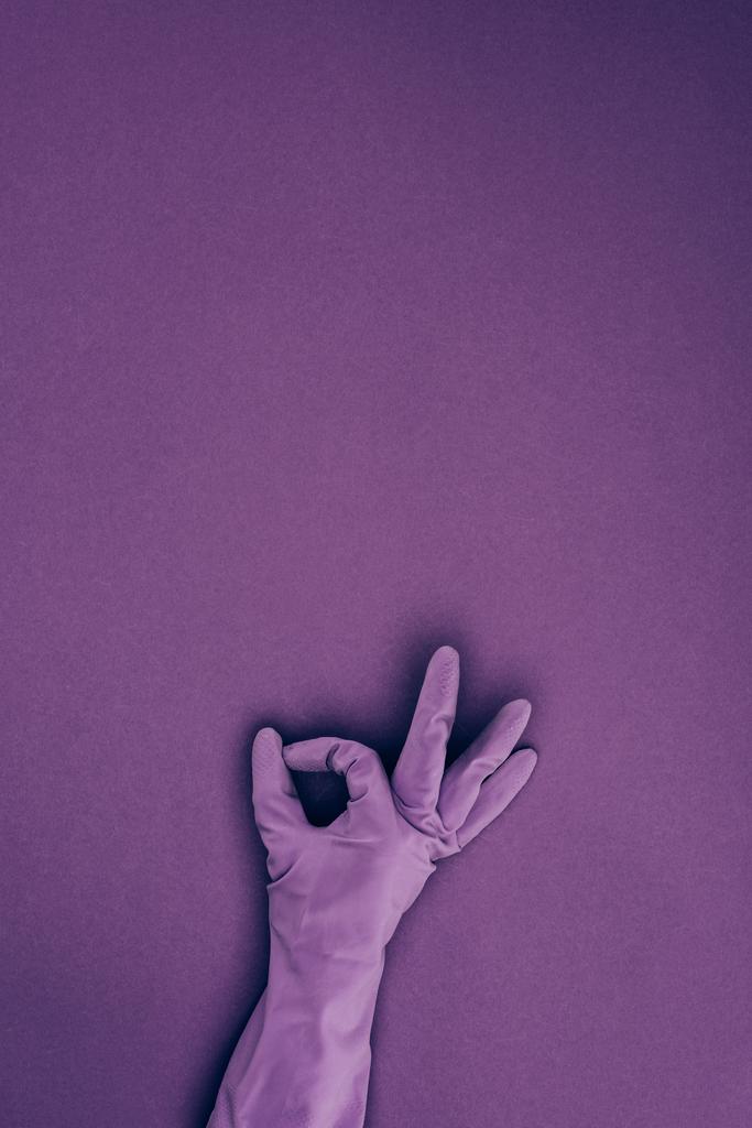 περικομμένη εικόνα της γυναίκας δείχνει εντάξει σημάδι στο ελαστικό προστατευτικό γάντι απομονώνονται σε βιολετί - Φωτογραφία, εικόνα