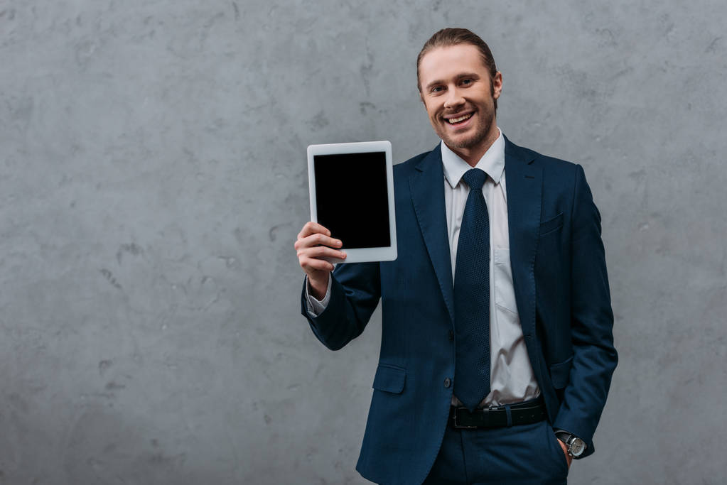 молодой улыбающийся бизнесмен показывает цифровой планшет на камеру
 - Фото, изображение