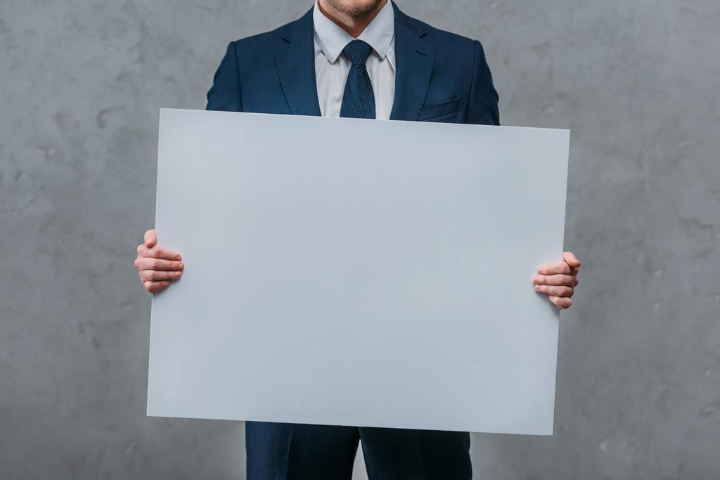 Oříznout záběr podnikatel drží prázdné desky před betonovou zeď - Fotografie, Obrázek