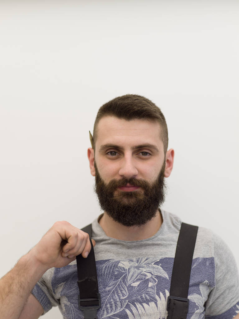 Portret van bebaarde hipster klusjesman met pen achter oor geïsoleerd op witte achtergrond - Foto, afbeelding
