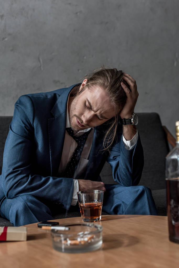 μεθυσμένος κατάθλιψη επιχειρηματία που κάθεται στον καναπέ με ποτήρι ουίσκι στο τραπέζι - Φωτογραφία, εικόνα