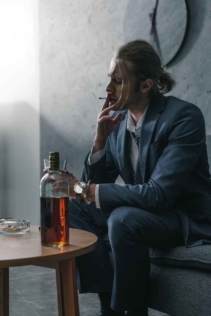 alcohol verslaafd zakenman met glas en fles whiskey roken sigaret - Foto, afbeelding