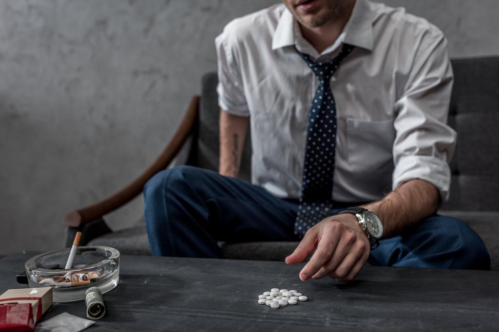 addicted junkie in white shirt and necktie taking mdma pill from table - Photo, Image