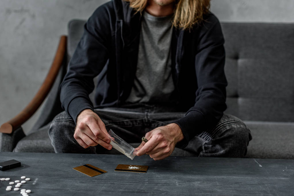 adicto hombre vertiendo cocaína en la tarjeta de crédito
 - Foto, Imagen