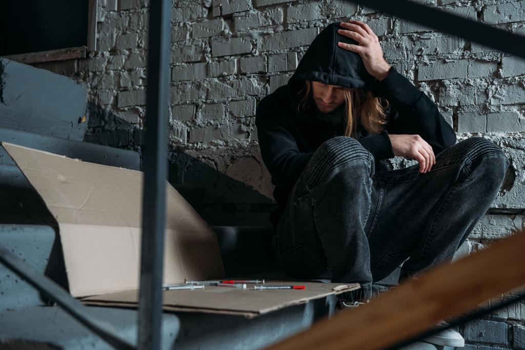 наркоман, сидящий на лестнице со шприцами
 - Фото, изображение