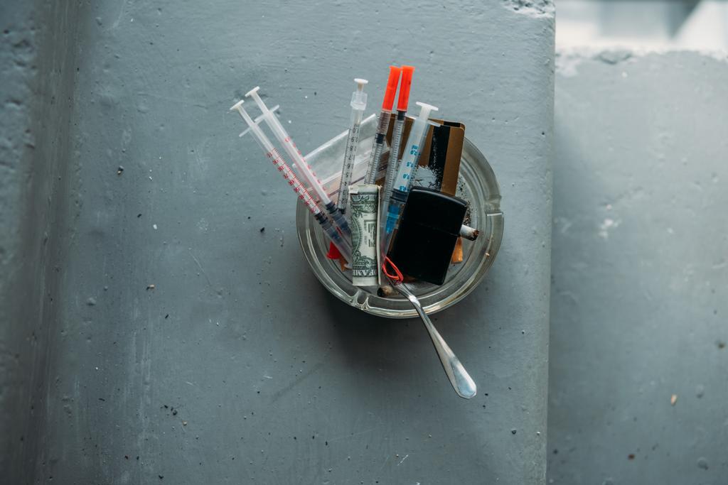 ylhäältä näkymä tölkki heroiini ruiskut ja erilaisia esineitä
 - Valokuva, kuva