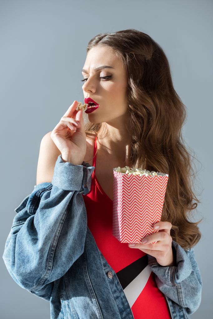 Atrakcyjna dziewczyna sexy z czerwonymi ustami jeść popcorn na szarym tle - Zdjęcie, obraz