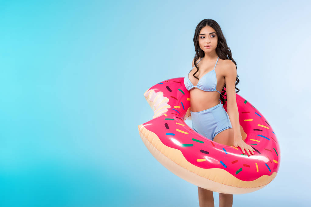 красива дівчина позує з надувним кільцем пончика, ізольована на синьому
  - Фото, зображення