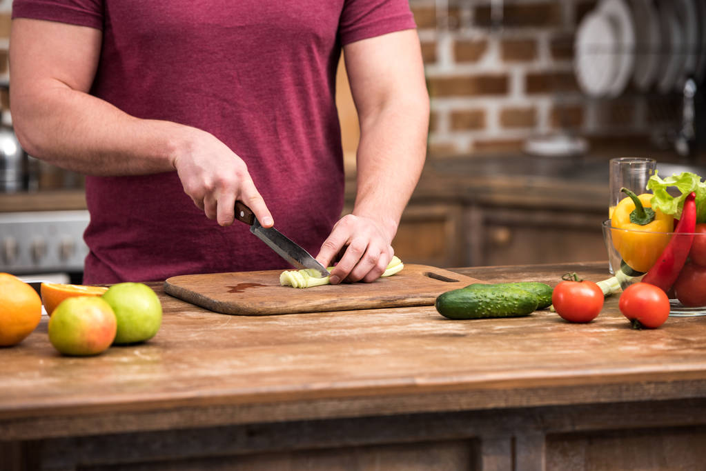vágott lövés a fiatalember vágás zeller, saláta, konyha főzés közben - Fotó, kép