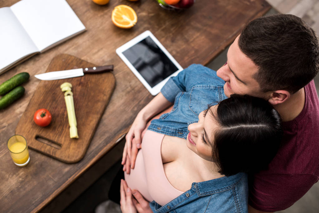 Szczęśliwa Młoda para w ciąży Ogarnięcie podczas gotowania razem, ogólny widok - Zdjęcie, obraz