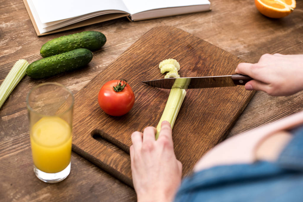cropped shot of woman cutting celery on wooden chopping board - Photo, Image
