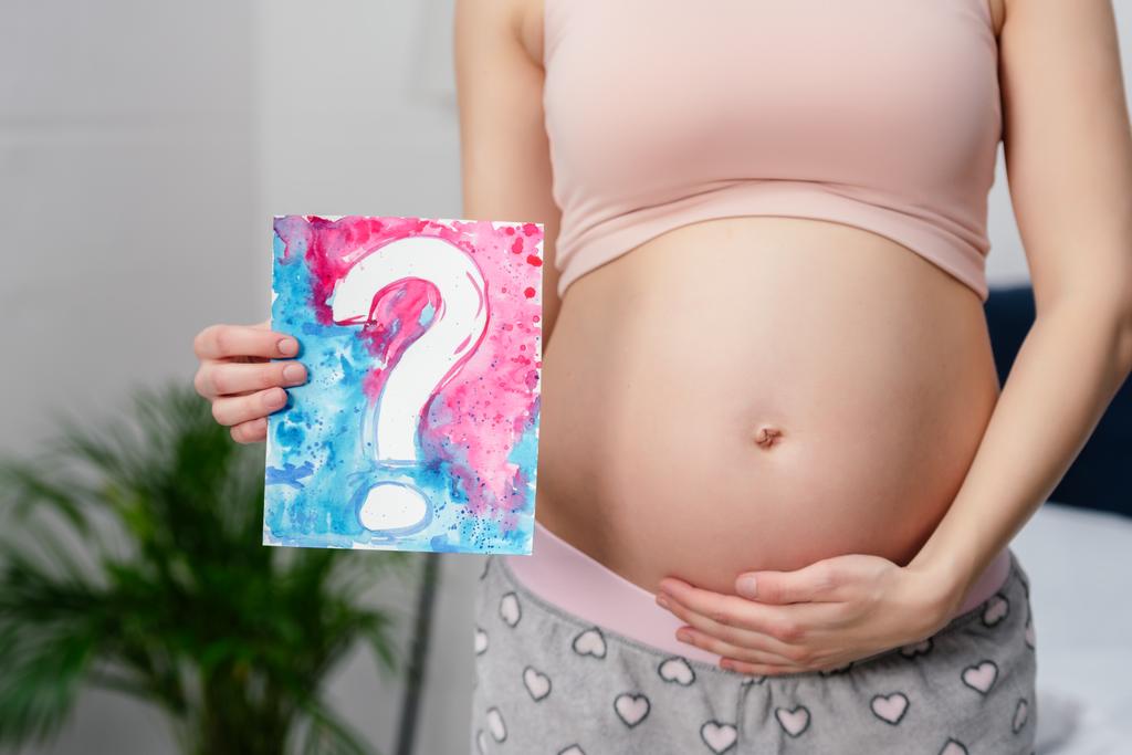 colpo ritagliato di donna incinta che tiene carta con punto interrogativo
 - Foto, immagini