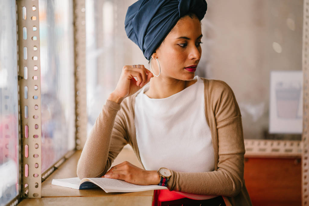 mladá, atraktivní muslimské ženy (arabské, Malajština, asijský) čte knihu u okna kavárny v den. Ona je nosit turban (šátek, hijabi) a je elegantně oblečená do zemitých tónů. - Fotografie, Obrázek