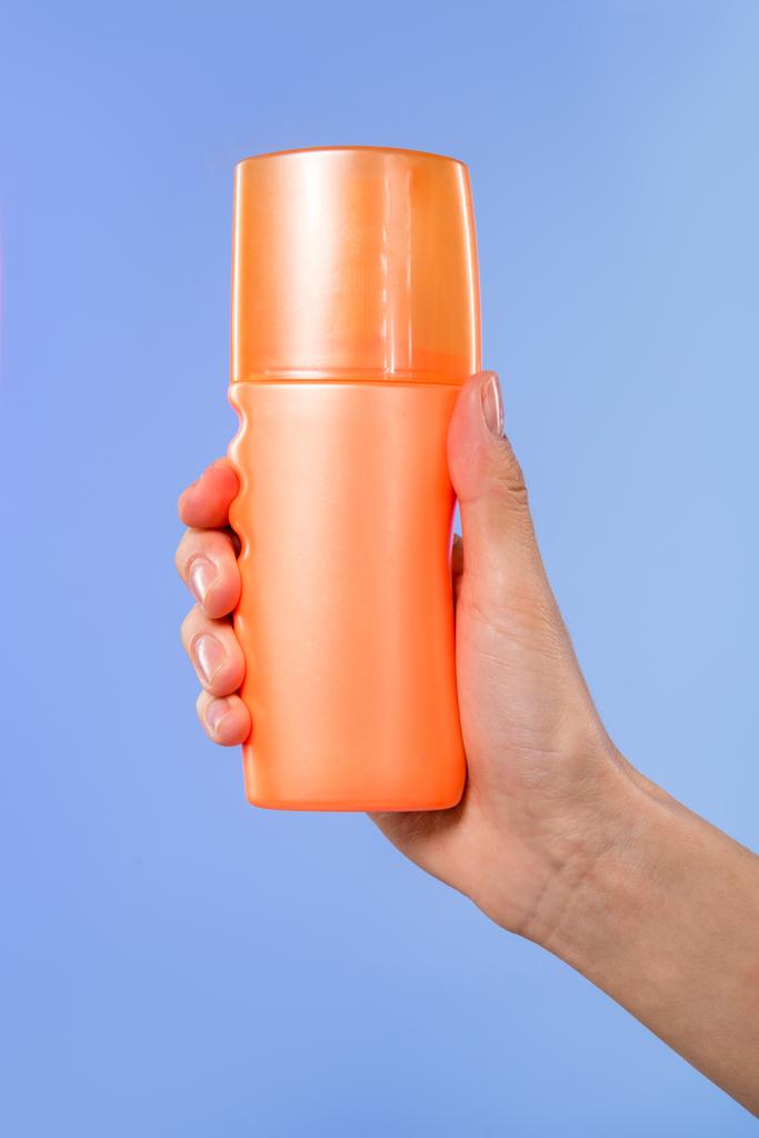 vista recortada de la mano femenina con botella de protector solar, aislado en azul
 - Foto, Imagen