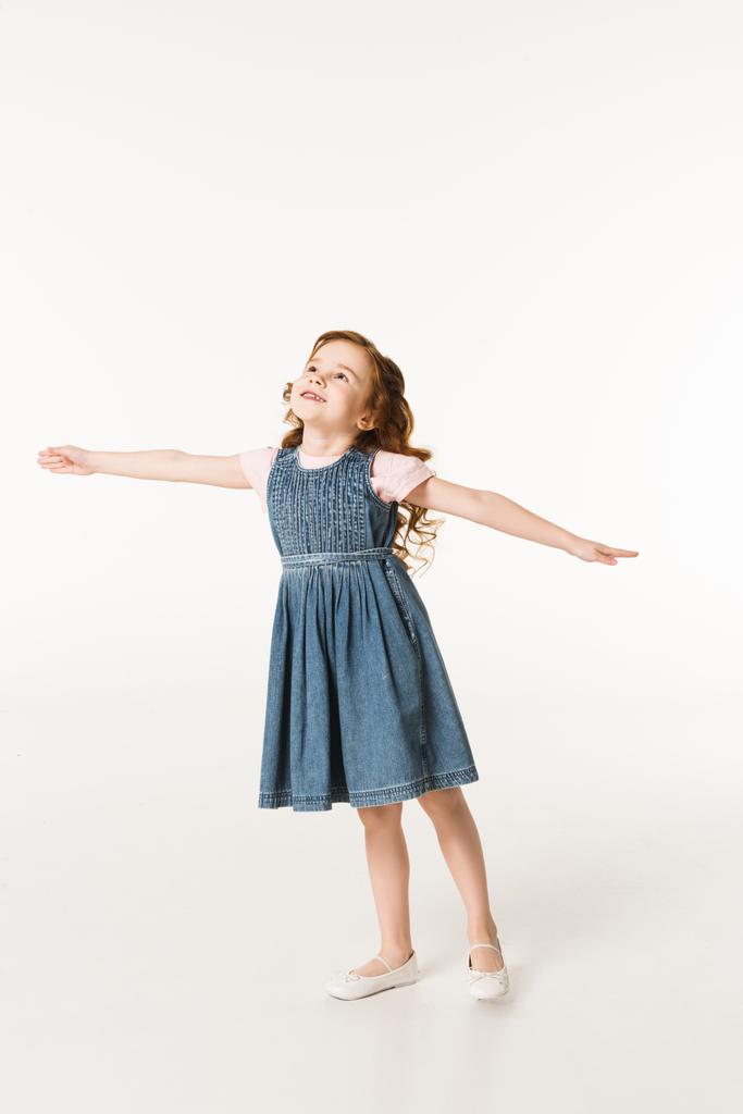 Kleines stylisches Kind im Kleid, das mit breiten Armen auf weißem Grund steht - Foto, Bild