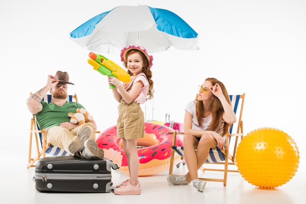 Famiglia di turisti con lettini prendisole, ombrellone, anello galleggiante e pistola ad acqua isolata su bianco
 - Foto, immagini