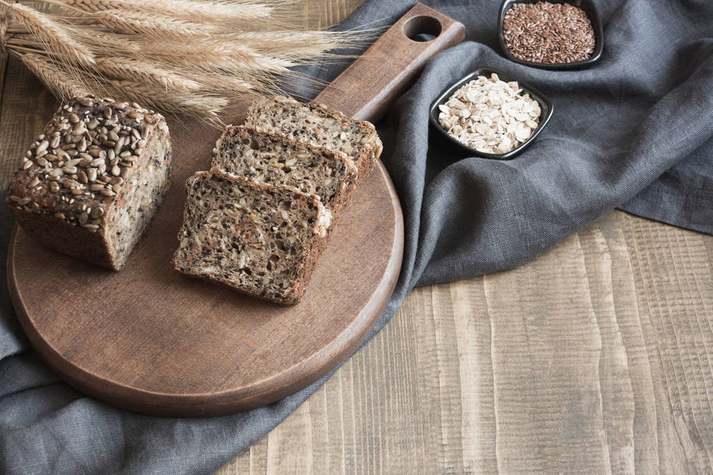 A loaf of fresh rustic rye bread on wooden board. Healphy food background. Close up. Copy space. Fitness wholegrain bread. - Photo, Image