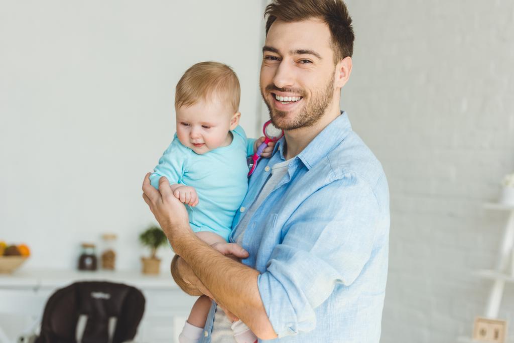 Sorridente giovane padre che tiene in mano la figlia neonata
 - Foto, immagini