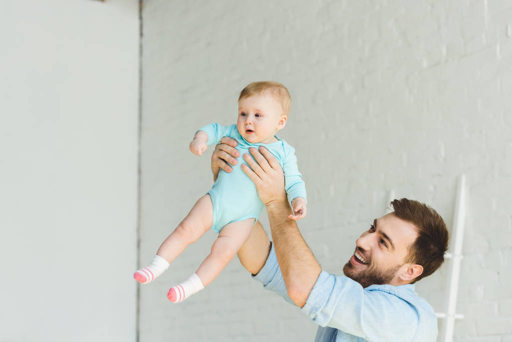 Gülümseyen baba havada bebek kızı yetiştirme  - Fotoğraf, Görsel