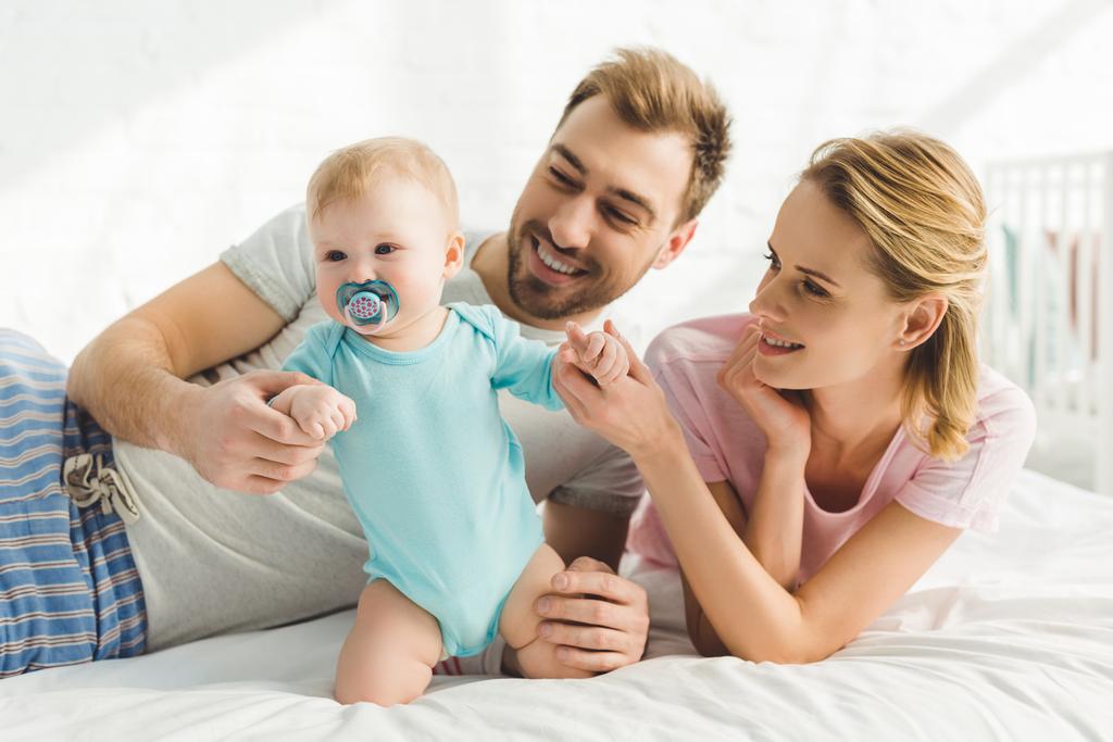 Sonrientes padres sosteniendo a su hija con muñeco de bebé
 - Foto, Imagen