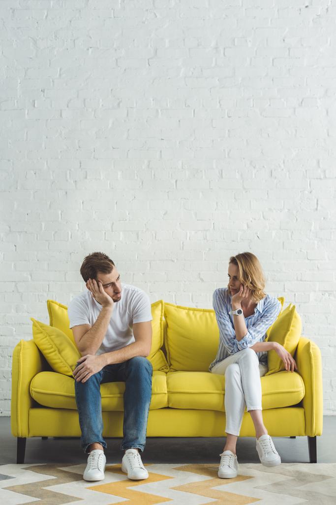 Young couple sitting on yellow sofa in modern room - Photo, Image