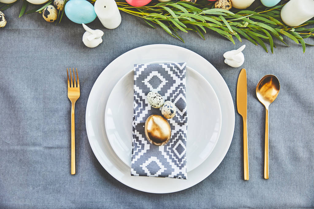 вид на золотые пасхальные яйца и перепелиные яйца на праздничных тарелках в ресторане
 - Фото, изображение