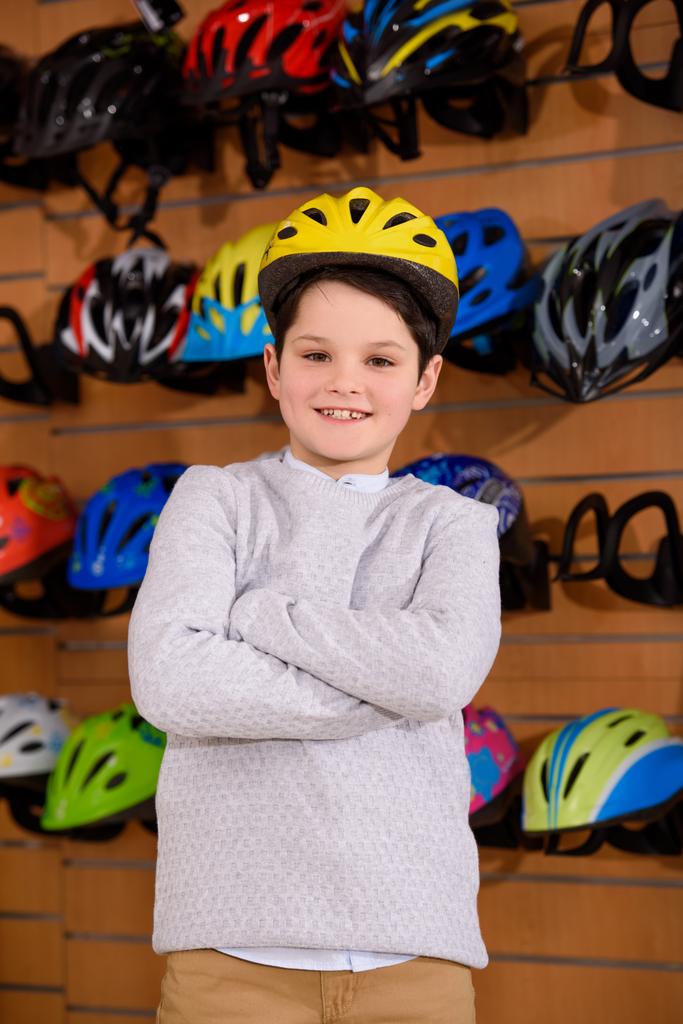 carino bambino indossando casco per bicicletta e sorridendo alla macchina fotografica in negozio di biciclette
  - Foto, immagini
