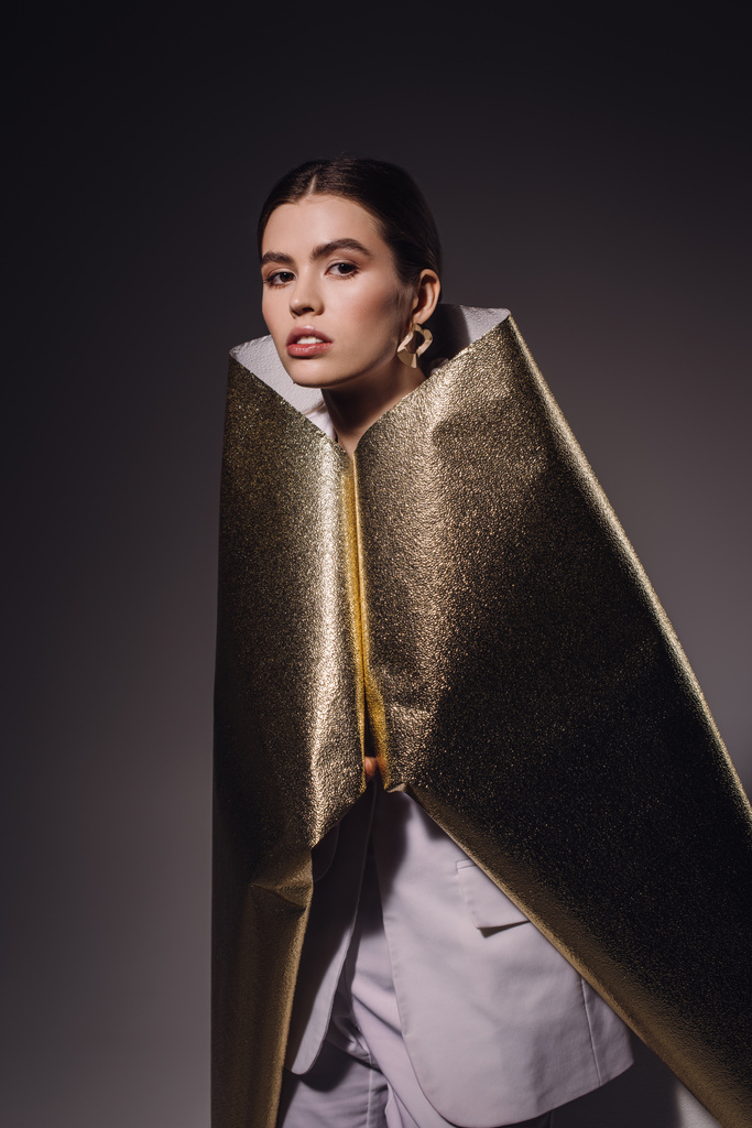portrét módní ženy v golden balicí papír pózuje na tmavé pozadí - Fotografie, Obrázek