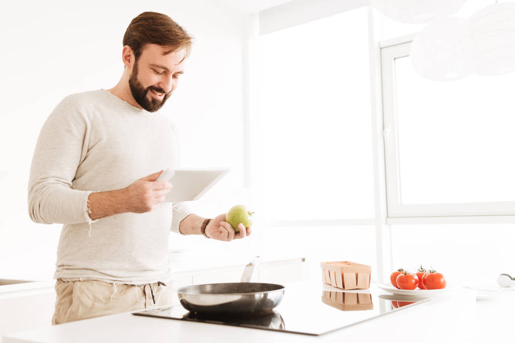 Image of young single man wearing casual clothing cooking in kit - Photo, Image