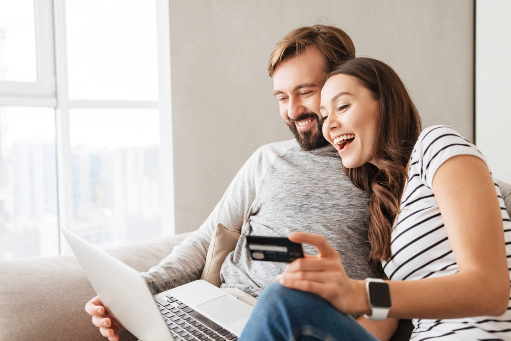 Portrait of a laughing young couple shopping online - Photo, Image